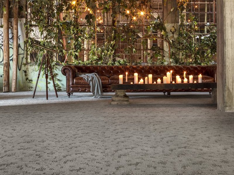 brown leather couch and a table with candled in a big open space room with beige carpet