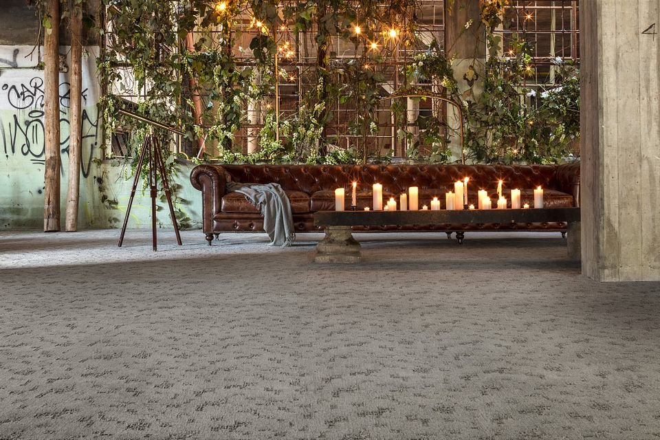 brown leather couch and a table with candled in a big open space room with beige carpet